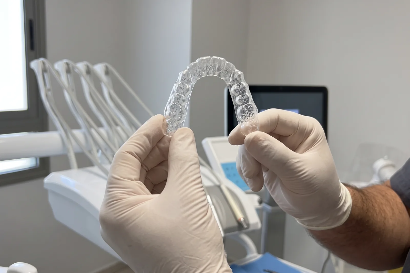 Mani con guanti che tengono una mascherina trasparente per l'allineamento dei denti